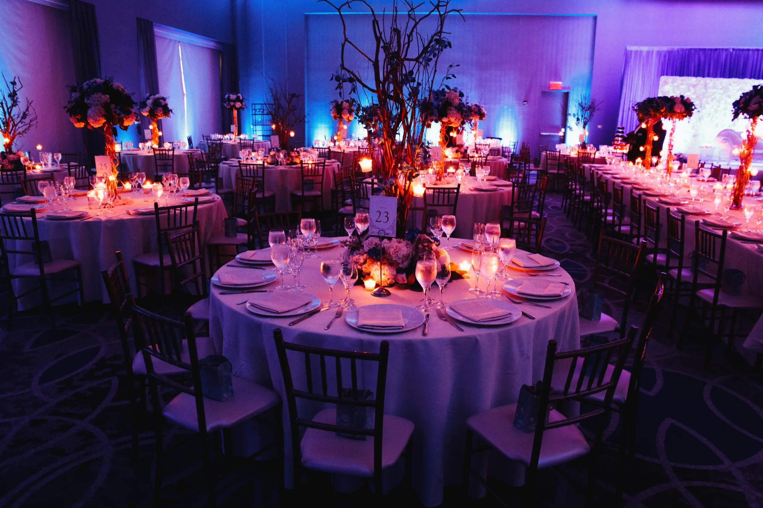 Decorated event hall with candlelit round tables and centrepieces